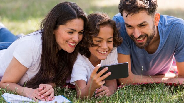 Parents and child watching something on smartphone while at the park