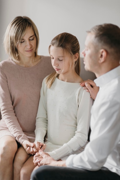 Parents and daughter praying together at home