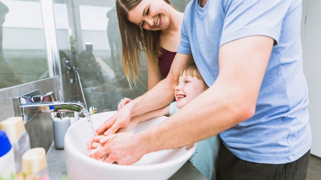 Parents and girl washing hands