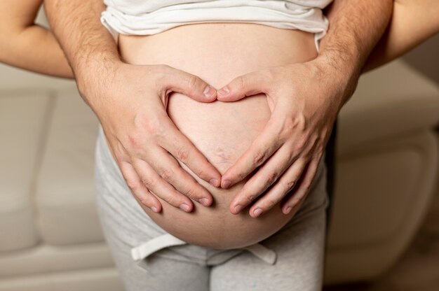 Parents hands making a heart on the belly