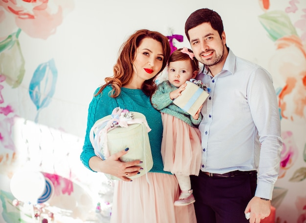 Parents hold their little daughter posing with present boxes 