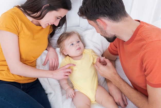 Free photo parents holding baby in bed