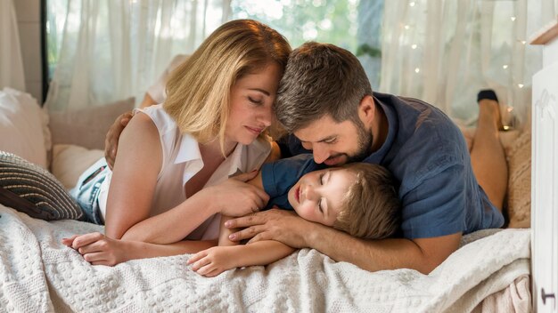 Parents hugging their son in bed