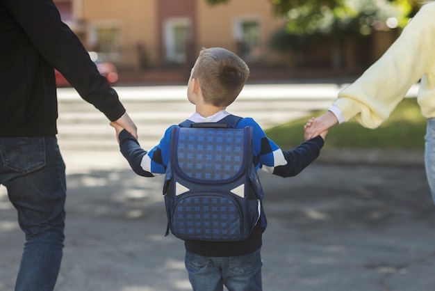 Parents and kid on first school day back view