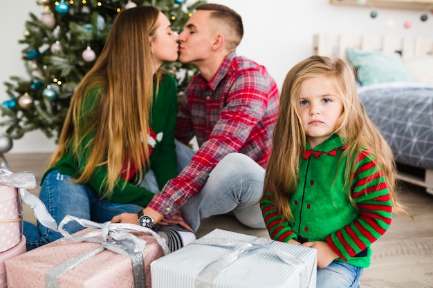 Parents kissing in front of christmas tree