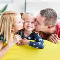 Free photo parents kissing to their little daughter