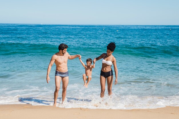 Parents lifting kid at the shoreline