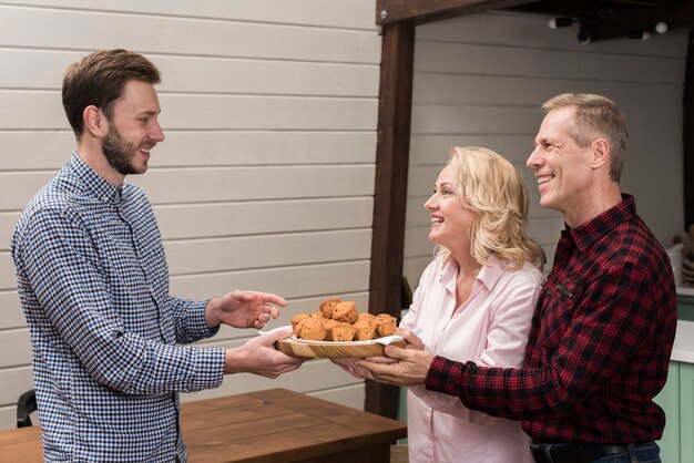 Parents offering son plate of muffins