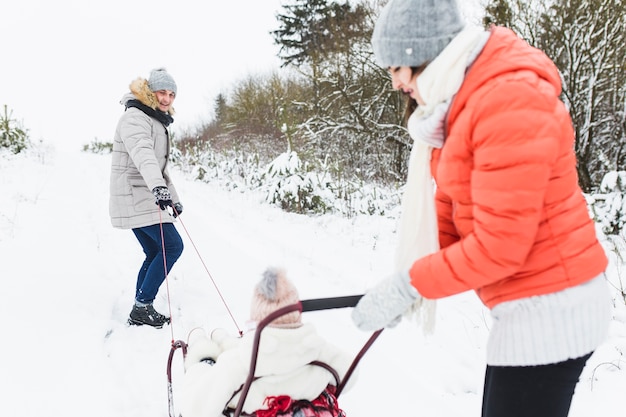 Parents pushing sleigh with daughter