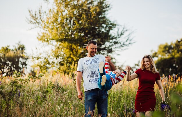 Parents raise their son up walking with him on the field 