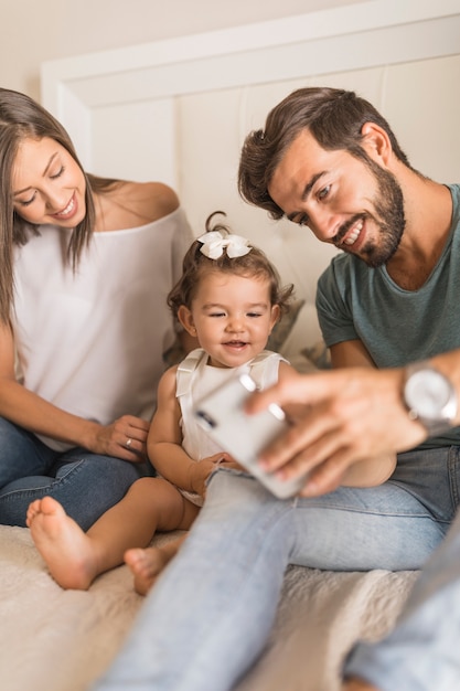 Parents showing smartphone to laughing daughter