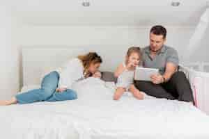 Free photo parents sitting in bed with kids