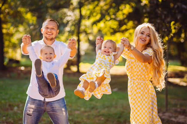 Foto gratuita i genitori oscillano i loro bambini che giocano nel parco