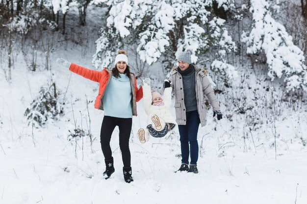 Parents swinging girl in winter