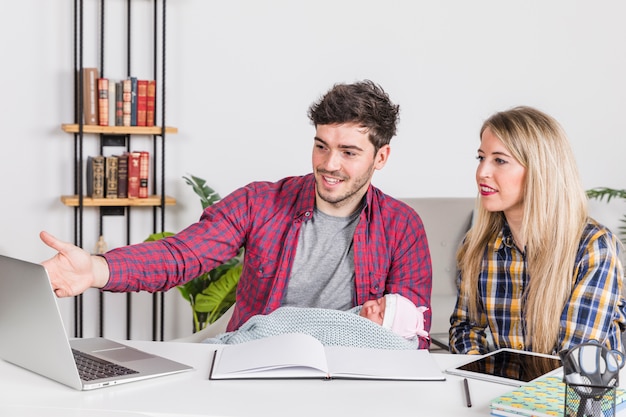 Free photo parents with baby looking at laptop screen