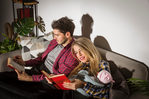 Parents with baby reading books on couch 