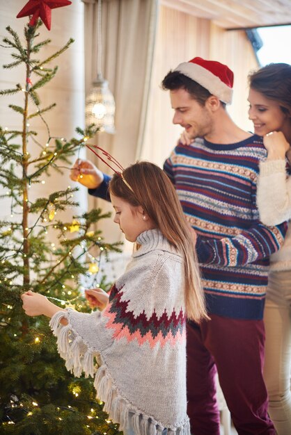 クリスマスの飾りをぶら下げている子供を持つ親