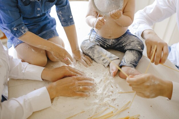 parents with children in the kitchen cook bread