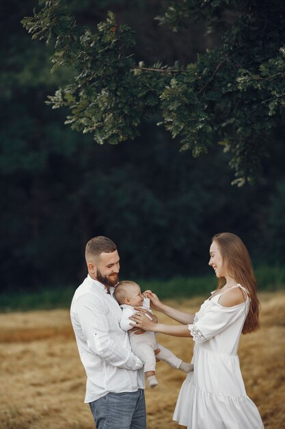 Parents with daughter. Family in a field. Newborn girl. Woman in a white dress.