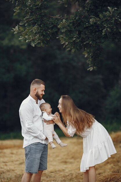 Parents with daughter. Family in a field. Newborn girl. Woman in a white dress.