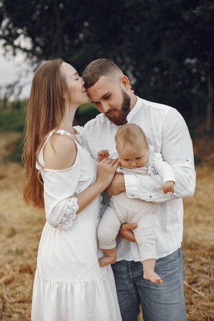 Parents with daughter. Family in a field. Newborn girl. Woman in a white dress.