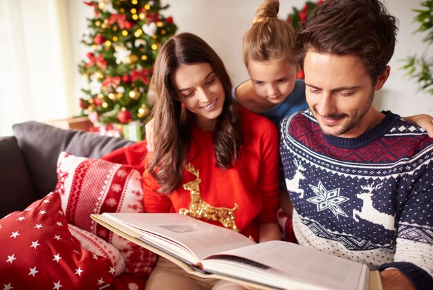 Parents with kid reading book at Christmas