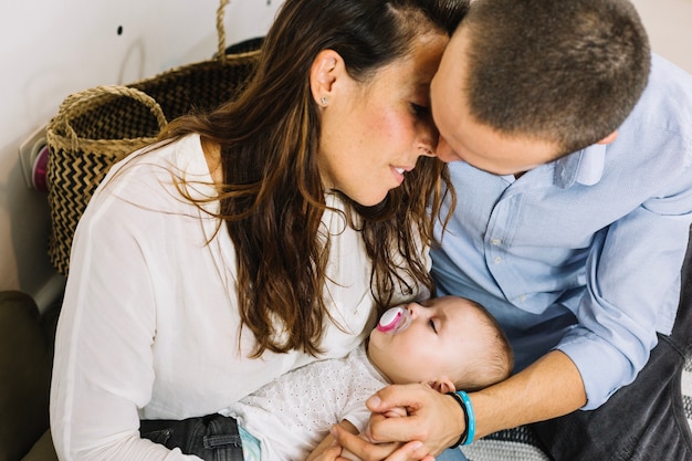 Parents with sleeping baby kissing