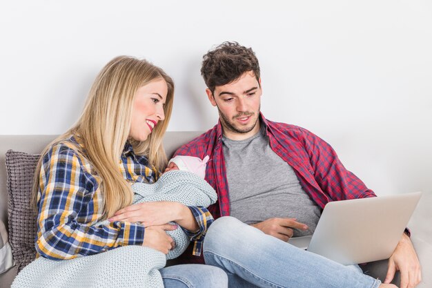 Parents with sleeping baby looking at laptop screen 