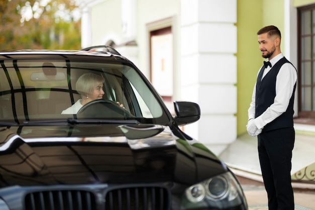 Parking valet welcoming woman with car