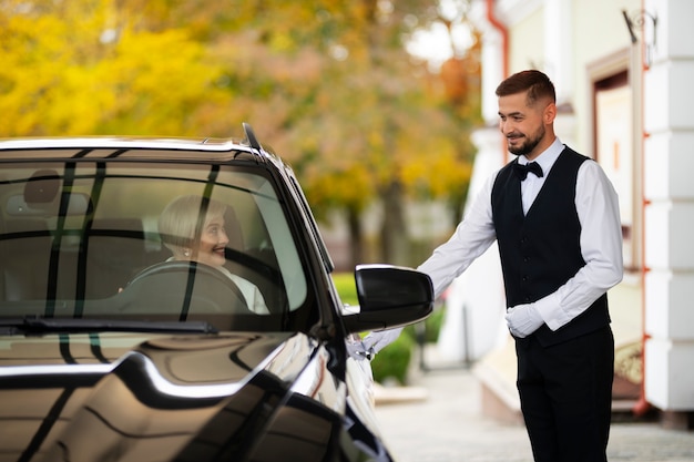 Parking valet welcoming woman with car