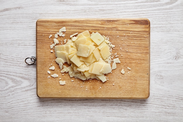 Parmigiano affettato, isolato sullo scrittorio di legno sulla tavola bianca