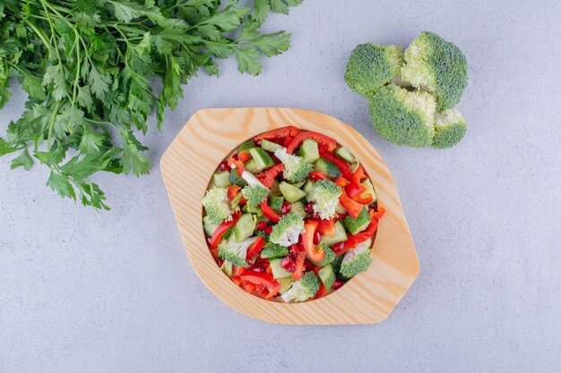 Parsley bundle, handful of broccoli and a platter of salad on marble background. High quality photo