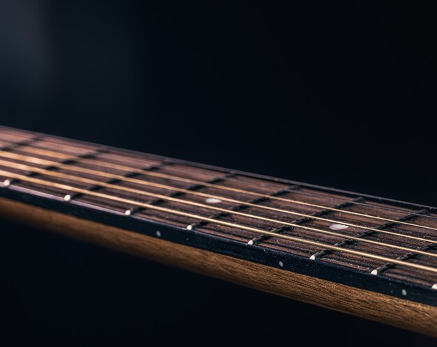 Part of an acoustic guitar, guitar fretboard on a black background.