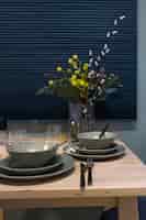 Foto gratuita parte di un tavolo da cucina di casa con piatti grigi e un bouquet in un vaso.