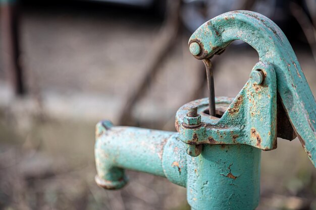 Часть старого синего железного водопроводного крана стоит снаружи