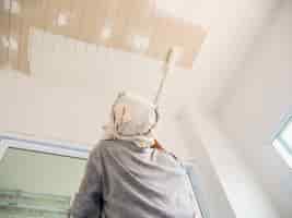 Foto gratuita foto a fuoco parziale di un uomo sta dipingendo il soffitto usando la spazzola a rullo