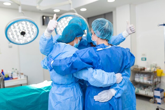 Partial view of hardworking male and female hospital team in full protective wear standing together in group embrace