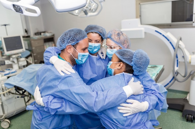 Free photo partial view of hardworking male and female hospital team in full protective wear standing together in group embrace