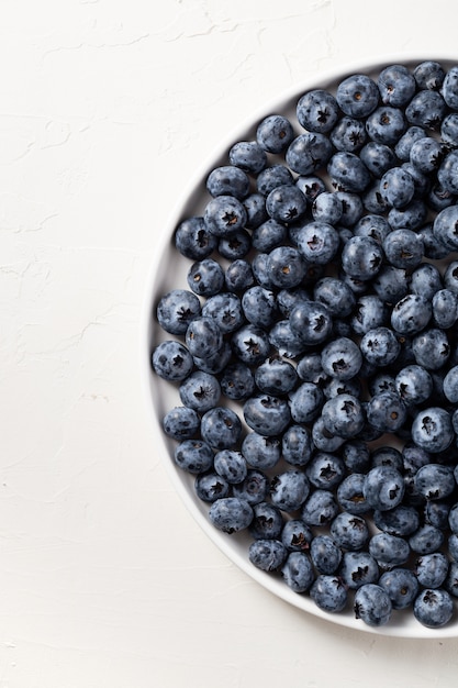 Free photo partial view of a white plate filled with blueberries on white