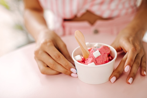 アイスクリームを食べる女性の部分図。甘いデザートを持つ女性の選択的な焦点。