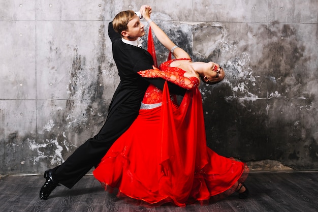 Foto gratuita partner che ballano la danza sensuale vicino al muro grigio