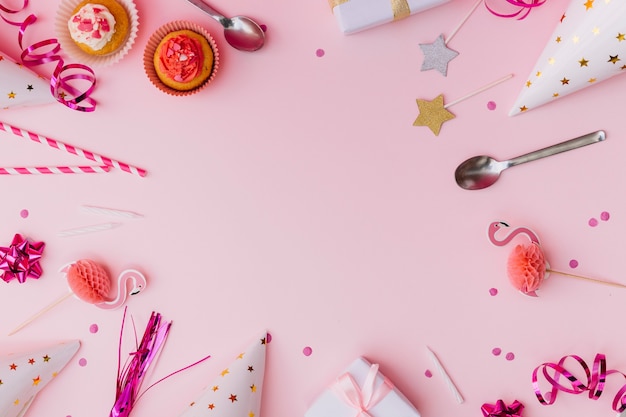 Foto gratuita accessori per feste con cupcake e cucchiaio sopra lo sfondo rosa