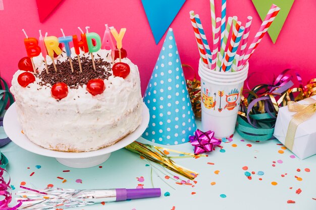 Party accessories with decorated cake on pink and blue background