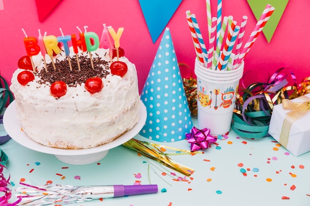 Party accessories with decorated cake on pink and blue background