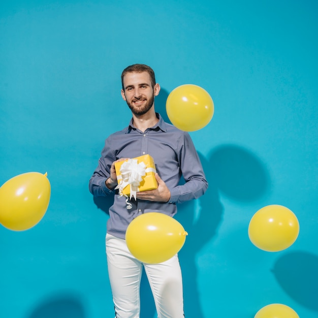 Free photo party boy posing with gift and balloons