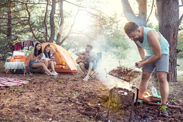 パーティー、森での男女グループのキャンプ。彼らはリラックスし、歌を歌い、バーベキューを調理します