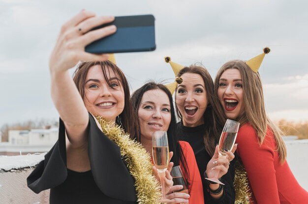 Ragazze da festa che prendono selfie di gruppo sul tetto