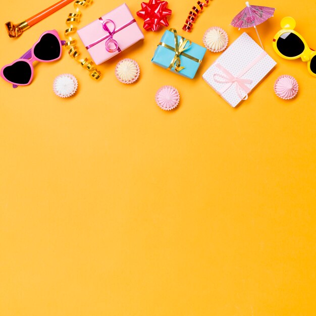 party horn; sunglasses; streamers; wrapped gift boxes; and aalaw on yellow backdrop