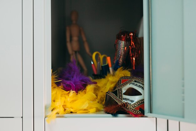 Party mask; yellow and purple feather boa in locker