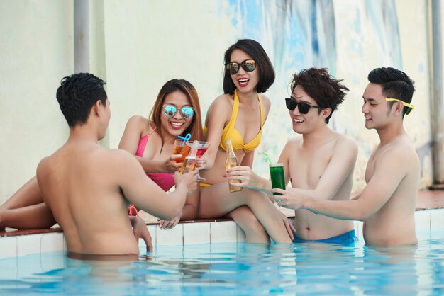 5 people in the pool holding cocktails